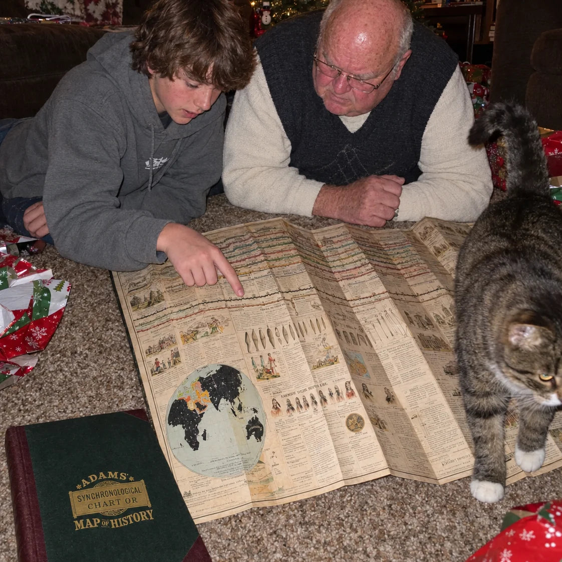 A grandfather and his teenage grandson on the carpet with the chart at Christmas